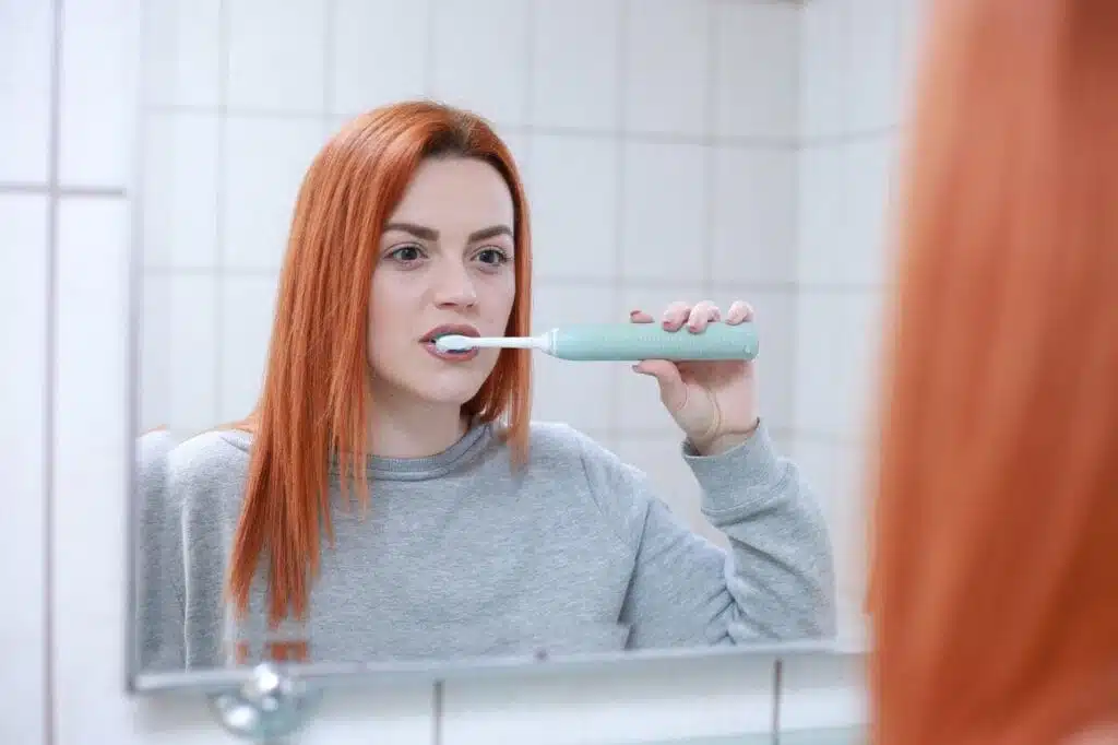 Mujer cepillandose los dientes con buena postura