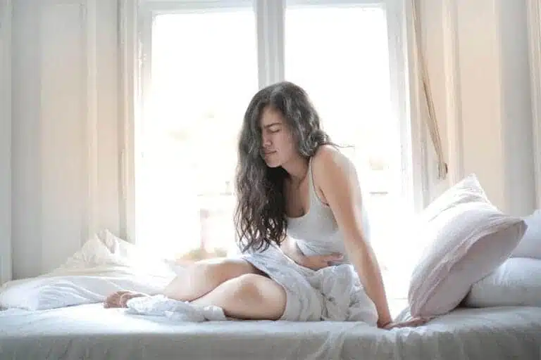 Mujer en la cama con dolor postoperatorio